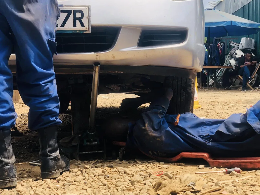 Mechanic in Nairobi Kenya fixing a car from underneath