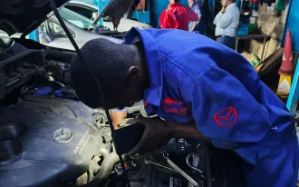 Mechanic in Nairobi from DOHC Auto servicing and detailing a Mazda engine