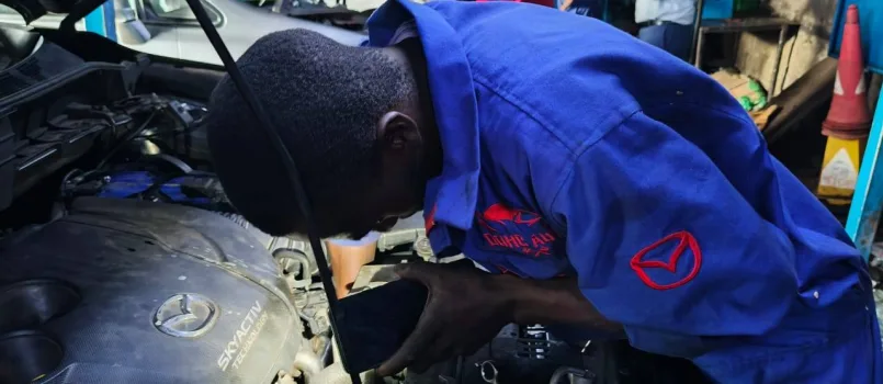 Mechanic in Nairobi from DOHC Auto servicing and detailing a Mazda engine