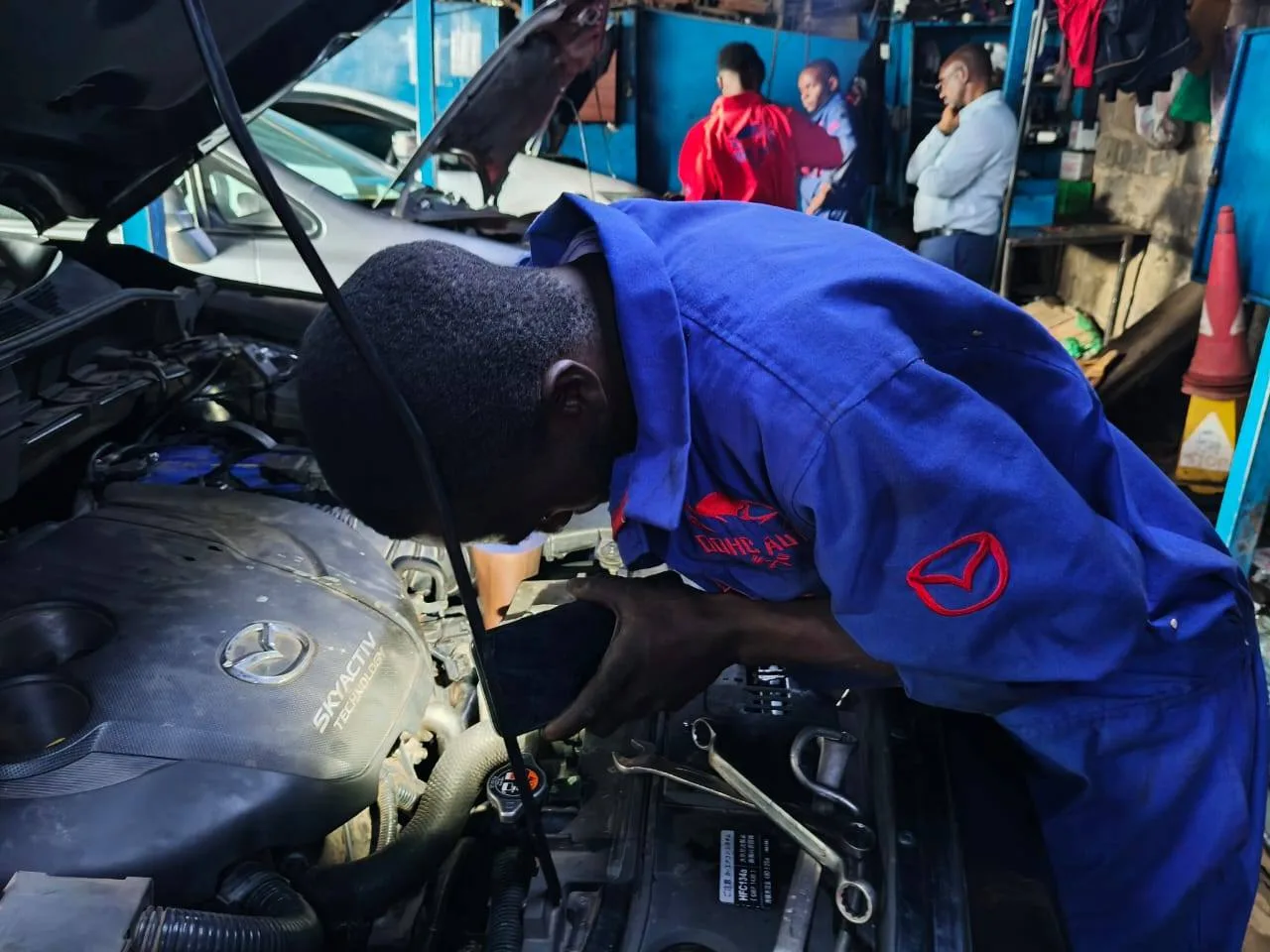 Mechanic in Nairobi from DOHC Auto servicing and detailing a Mazda engine